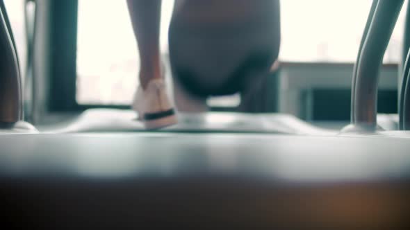 Back View on Man Feet Running on Trademill in Sport Club. Closeup Sportsman Legs alt