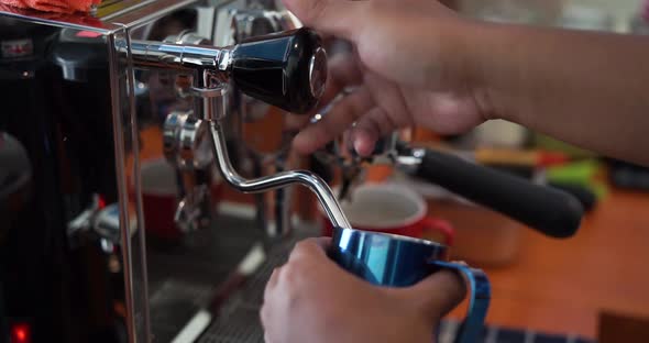 Barista preparing coffee in a coffee shop. Heating Soy Milk with Professional Coffee Machine for Cap alt