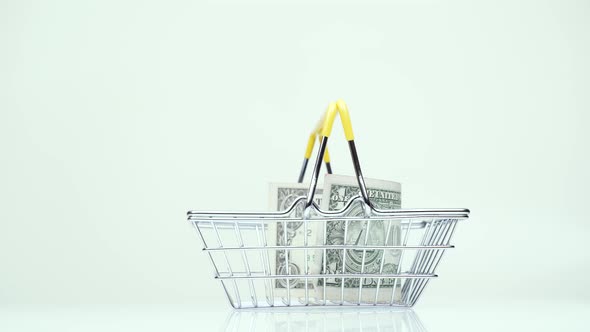 Supermarket Basket with One Dollar Money Rotates on a White Background