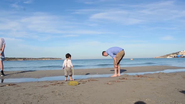 LONG SHOT moving away from camera Father and son playing on the beach of Malta on a clear beautiful alt