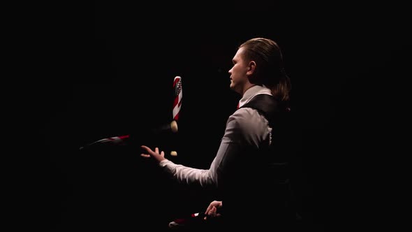 Camera Rotates Around Concentrated Man Professionally Juggling and Balancing Pins alt