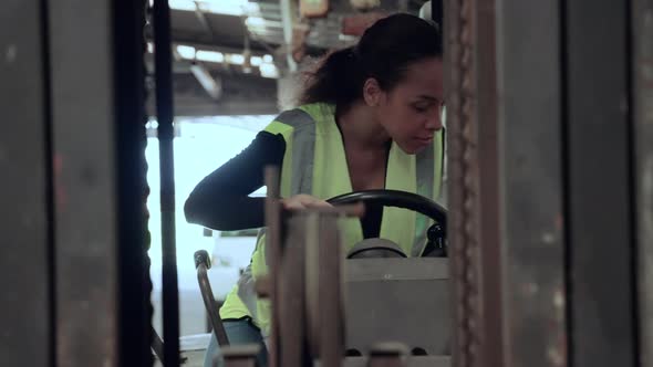 African American female worker gets into a forklift to drive a warehouse