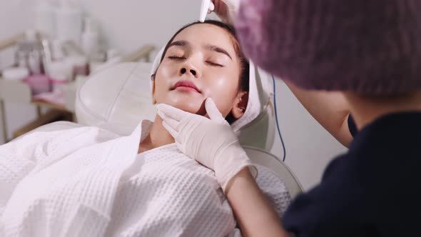 Beauty clinic concept. Young woman getting professional facial procedure. alt