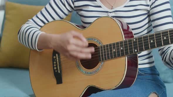Close Up Of Woman's Hands Playing A Guitar At Home alt
