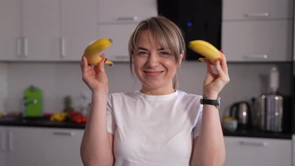 Playful Female Having Fun with Bananas in Kitchen alt