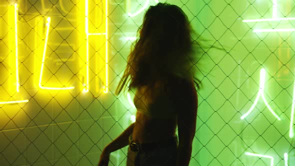 Woman Dancing Against Illuminated Neon Wall