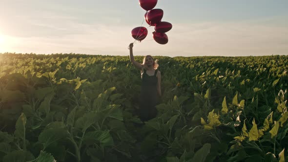 Attractive Woman in Feminine Midi Dress Having Fun with Heart-shaped Balloons on Green Nature alt