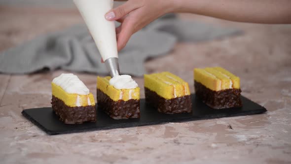 Female hands decorate a sponge cakes with cream from a pastry bag with a nozzle.