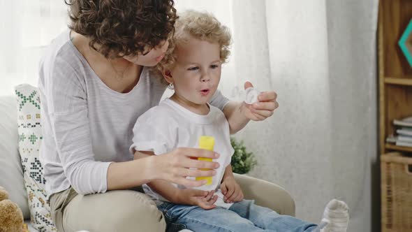 Mother Teaching Toddler Boy to Blow Bubbles alt