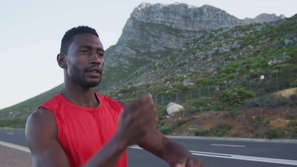 Portrait of african american man wearing sports clothes and stretching on a country road alt