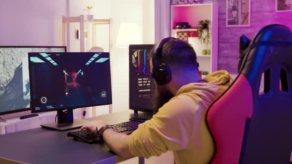 Man in a Room with Colorful Neon Lights Sitting on Gaming Chair alt