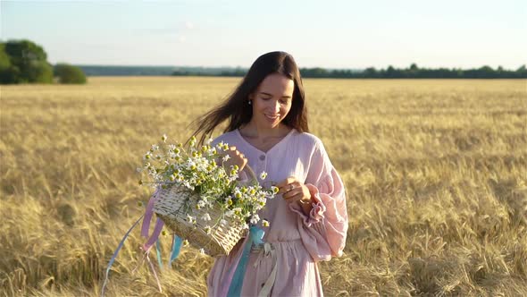 Beautiful Girl in Wheat Field with Ripe Wheat in Hands