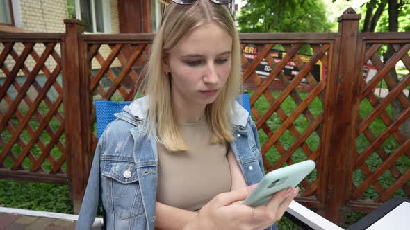Relaxed young girl using smartphone surfing social media, close up alt