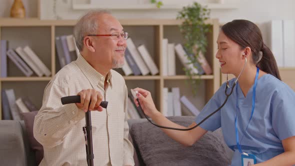 Female doctor use stethoscope to examine Asian elderly patient heartbeat. Caring female doctor use t alt