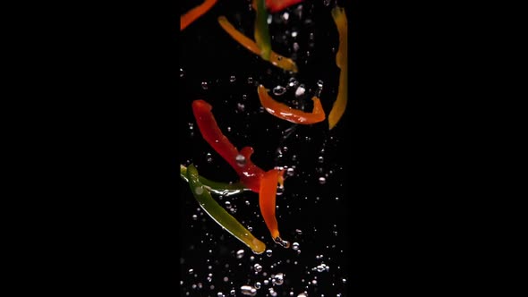 Bell peppers flying in the air splashing with water in slowmotion alt