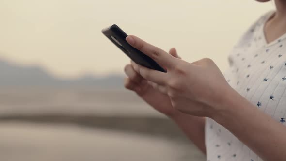 Close up Asian teenage woman using smartphone in vacation holiday typing messages.