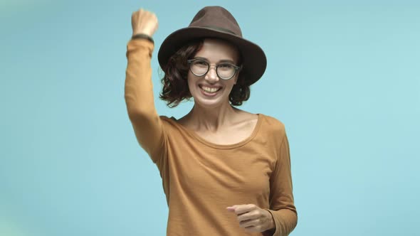 Beautiful Girl in Glasses and Hipster Hat Making Fist Pump with Joy and Screaming Yes Celebrating