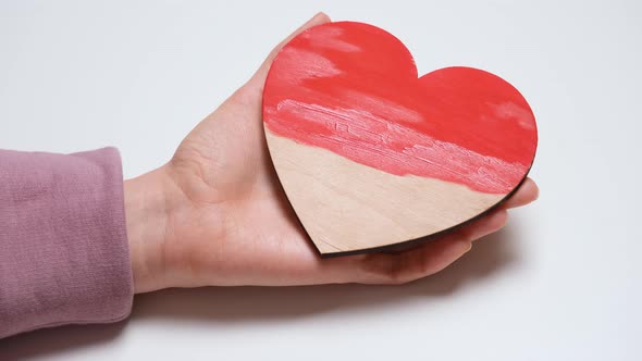 Hand Paints a Wooden Heart in Red