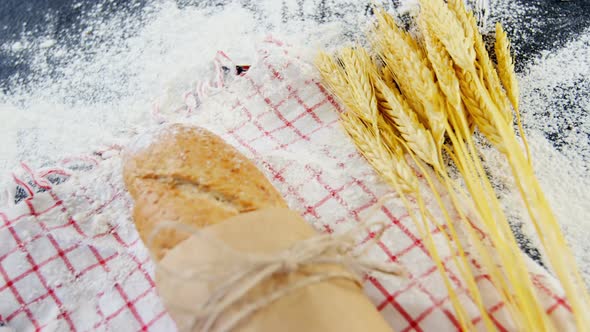 Baguette wrapped in paper, wheat grains and flour alt