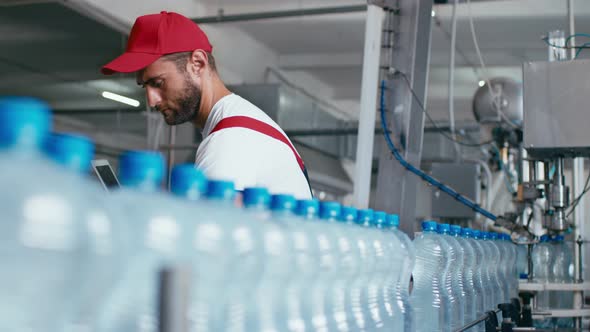 Young Man Worker of Water Factory Checking Quality and Making Inspection in Line Production