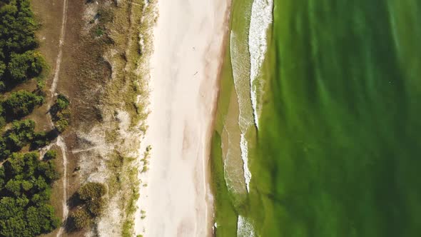 AERIAL: Flying extremely high over the sunny sandy beach alt