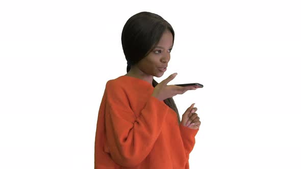 Pretty African American Woman in Bright Jumper Dictating Message Using Her Phone on White Background alt