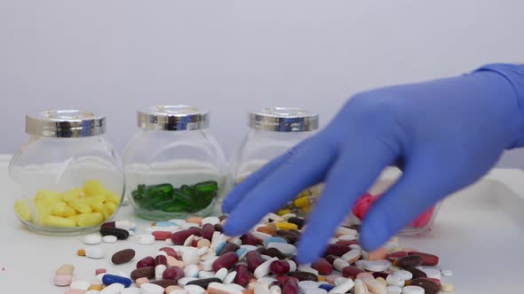 Mixing different colors tablets and picking up one white tablet from bunch alt