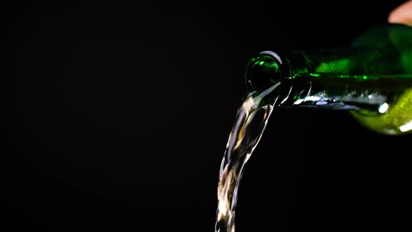 Stream of Beer Runs Through the Open Green Glass Bottle in Slow Motion Video