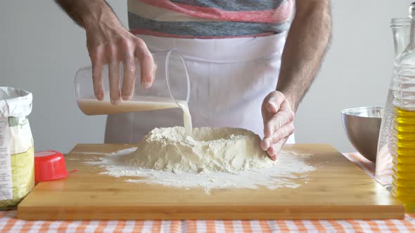 Man pouring water in flour for preparing pizza dough