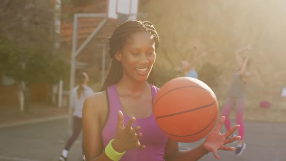 Portrait of african american female basketball player holding ball and looking at camera alt