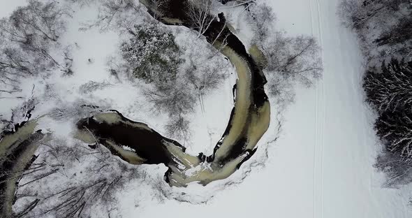 Flying Over Dark Black River and Snow Covered Land alt