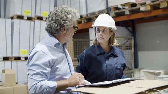 Focused Inspector and Female Worker Talking in Stock alt