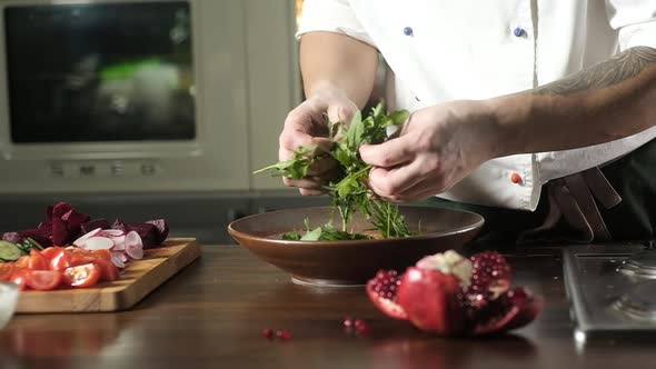 preparation of salad. Arugula with vegetables. chef is stirring fresh salad. alt