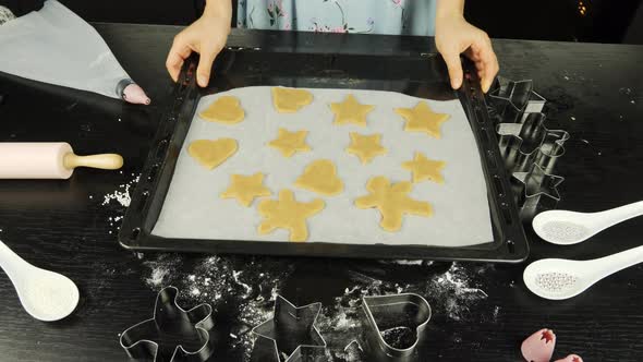 Cookies in different shapes of raw dough on baking sheet alt