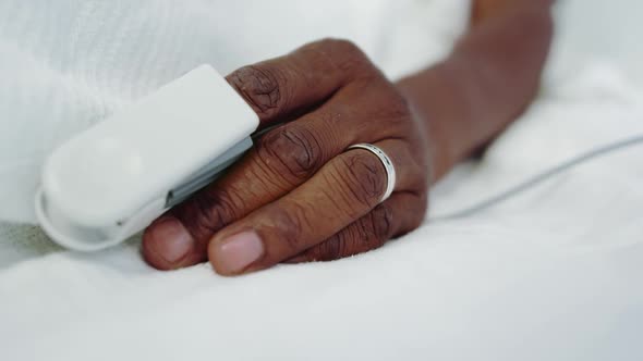 Close-up of pulse oximetry on African american male patient hand in the ward at hospital alt