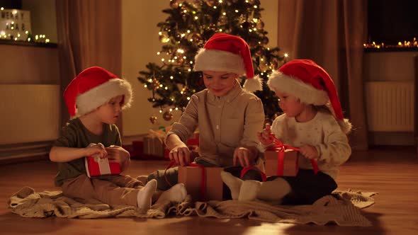 Happy Children Opening Christmas Gifts at Home