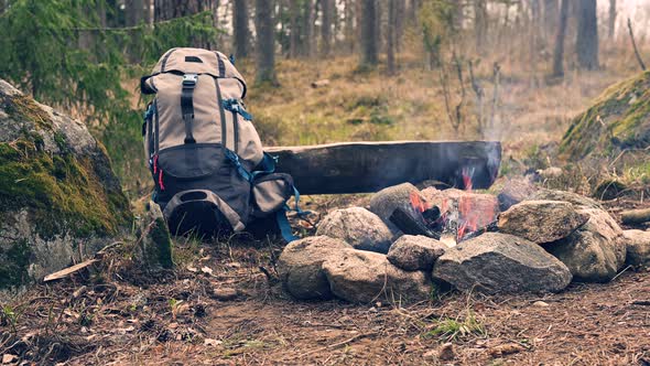 Backpack and campfire in the forest