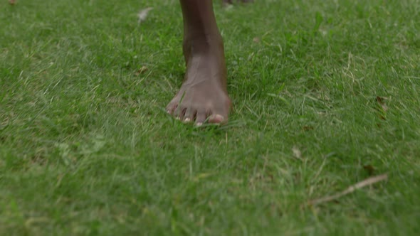 Close Up of Woman Legs Walking on Grass with Barefoot During Warm Summer Day alt