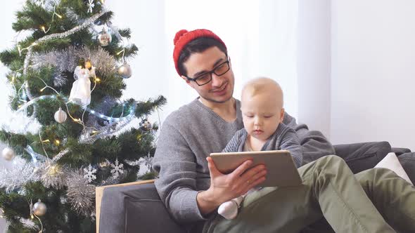 Young Father with Little Son Playing on Tablet Computer Christmas