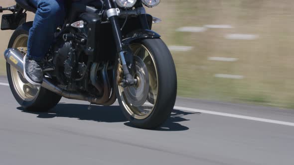 Tracking shot of man riding motorcycle on country road.  Fully released for commercial use.