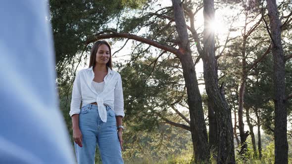Yong Beautiful Woman Posing and Smiling to the Man in the Park in Summer Weather alt