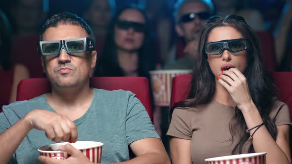 Closeup Focused Unbelievable Hispanic Couple Watching Interesting Film in 3D Glasses Eating Popcorn alt