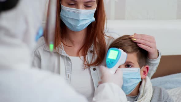 Doctor in Protective Suit Against Virus and Infection Provides Medical Care To Female Parent alt