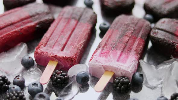 Homemade Blackberry and Cream Ice-creams or Popsicles with Frozen Berries on Black Slate Tray alt
