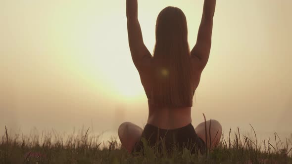 Woman is Engaged in Meditation on the Background of Sunset