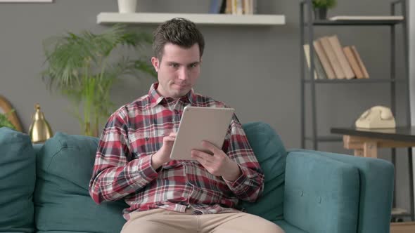 Man Having Loss on Tablet on Sofa alt