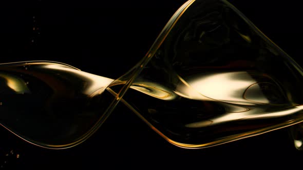 Super Slow Motion Shot of Swirling and Splashing Golden Oil Isolated on Black Background at 1000Fps alt