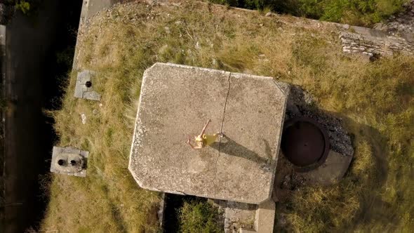 Aerial view of dancing blonde woman in a yellow dress  against the background of mountains alt