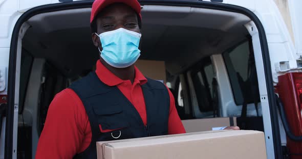 African man courier delivering packages with truck while wearing protective face mask alt