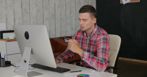 Man Makes Purchases Over the Internet on a Computer and Pays By Credit Card at the Office alt